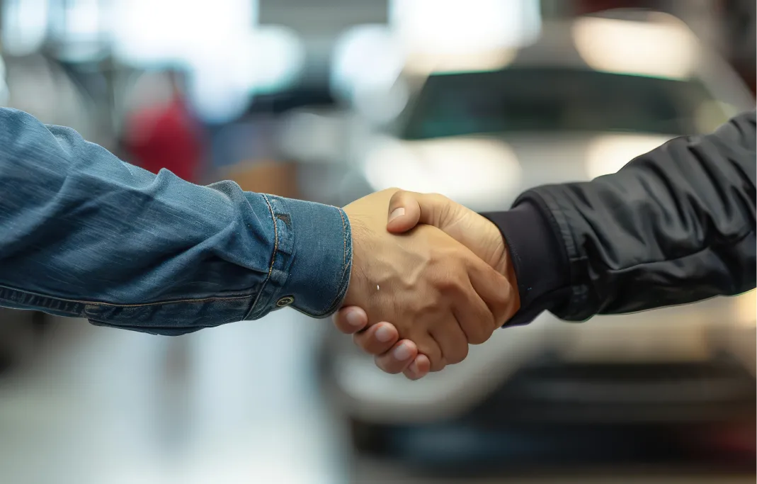 Customer shaking hands with a dealership team member after discussing a vehicle purchase.