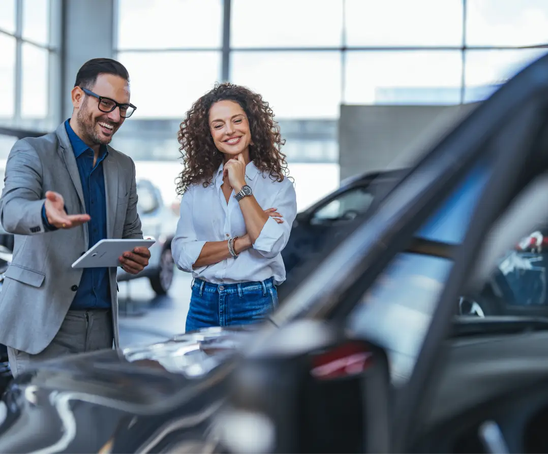 Dealership team member helping a customer explore vehicle options inside a showroom.