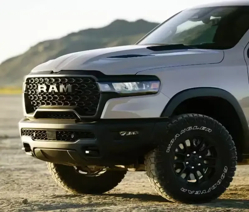 Close-up of a white Ram 1500 front grille and wheel on an off-road trail