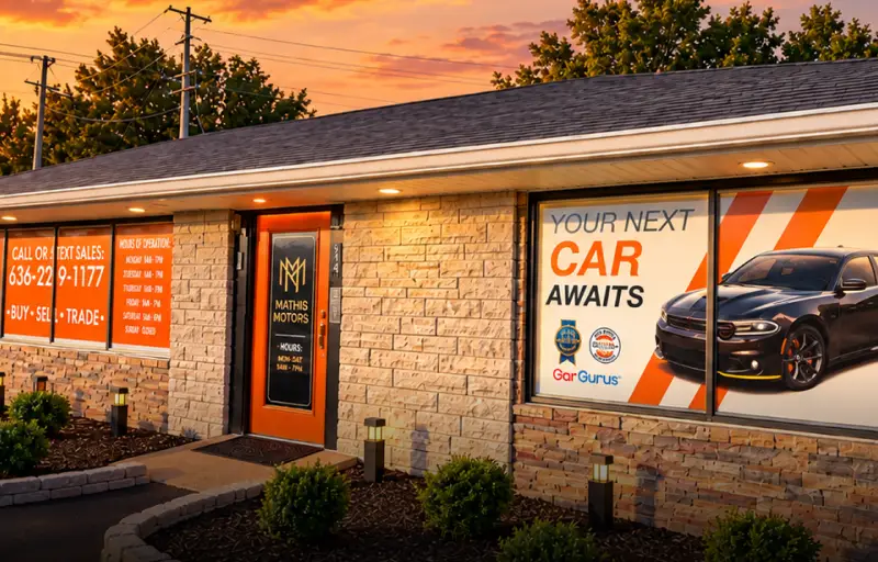 Mathis Motors dealership exterior featuring branded window graphics, an orange entrance, and landscaping.