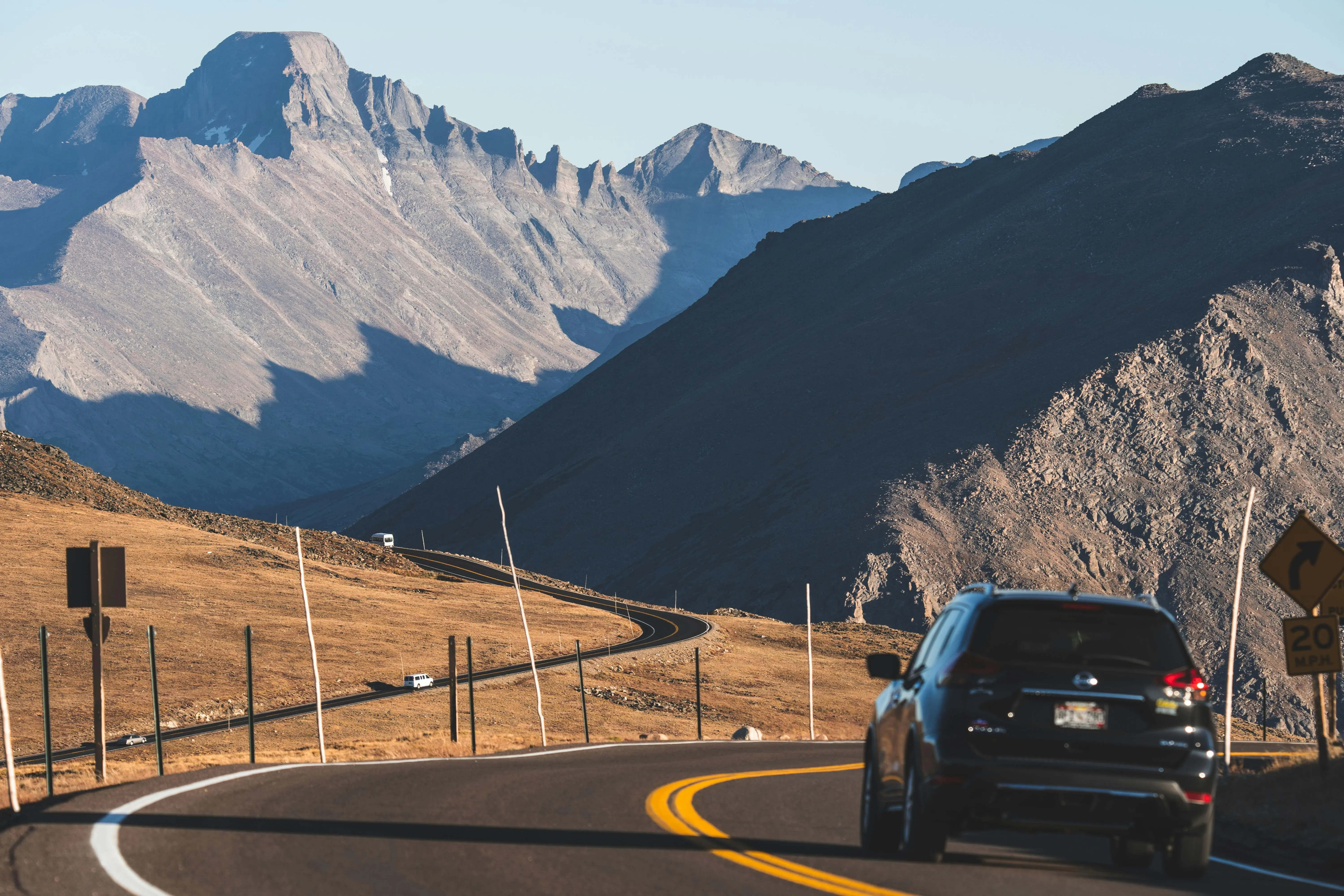 A black SUV driving a windy mountain road.