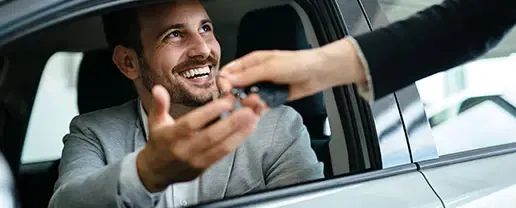 Customer handing vehicle keys to a friendly McCloskey Motors salesperson