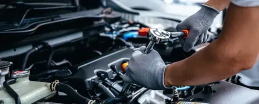Technician performing engine maintenance under the hood of a vehicle at McCloskey Service & Repair