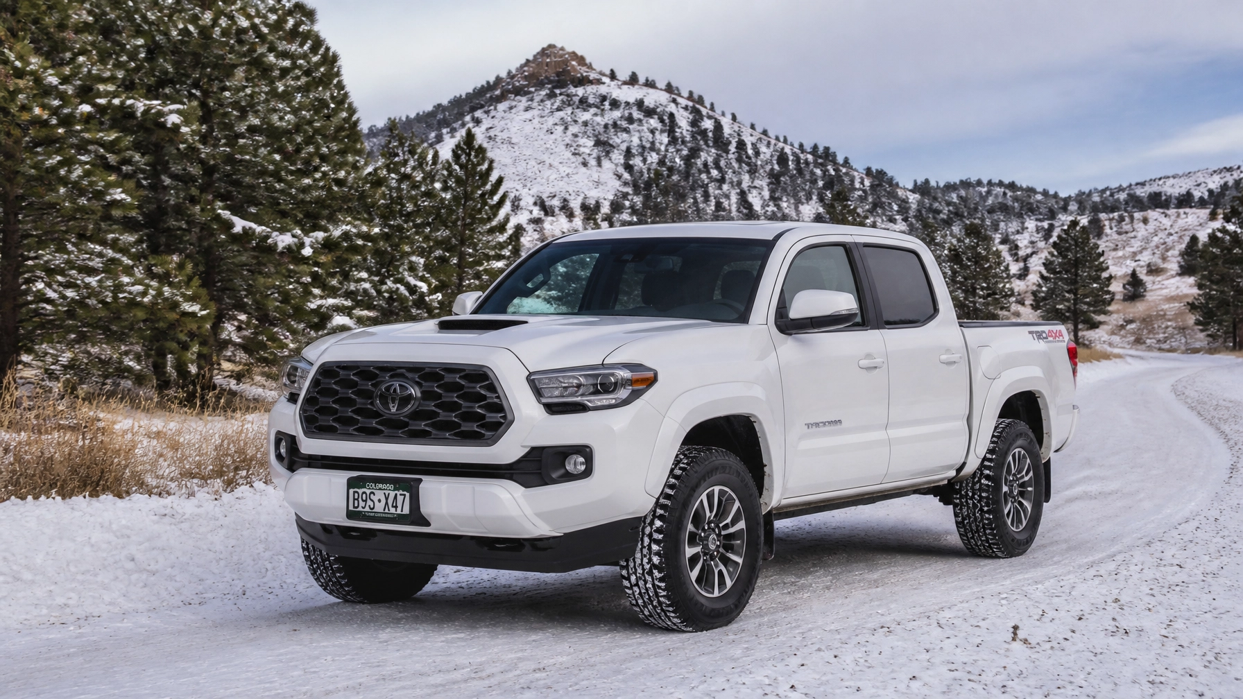 White Toyota Tacoma with 4WD parked on a snowy road in the Colorado foothills near Monument Hill CO