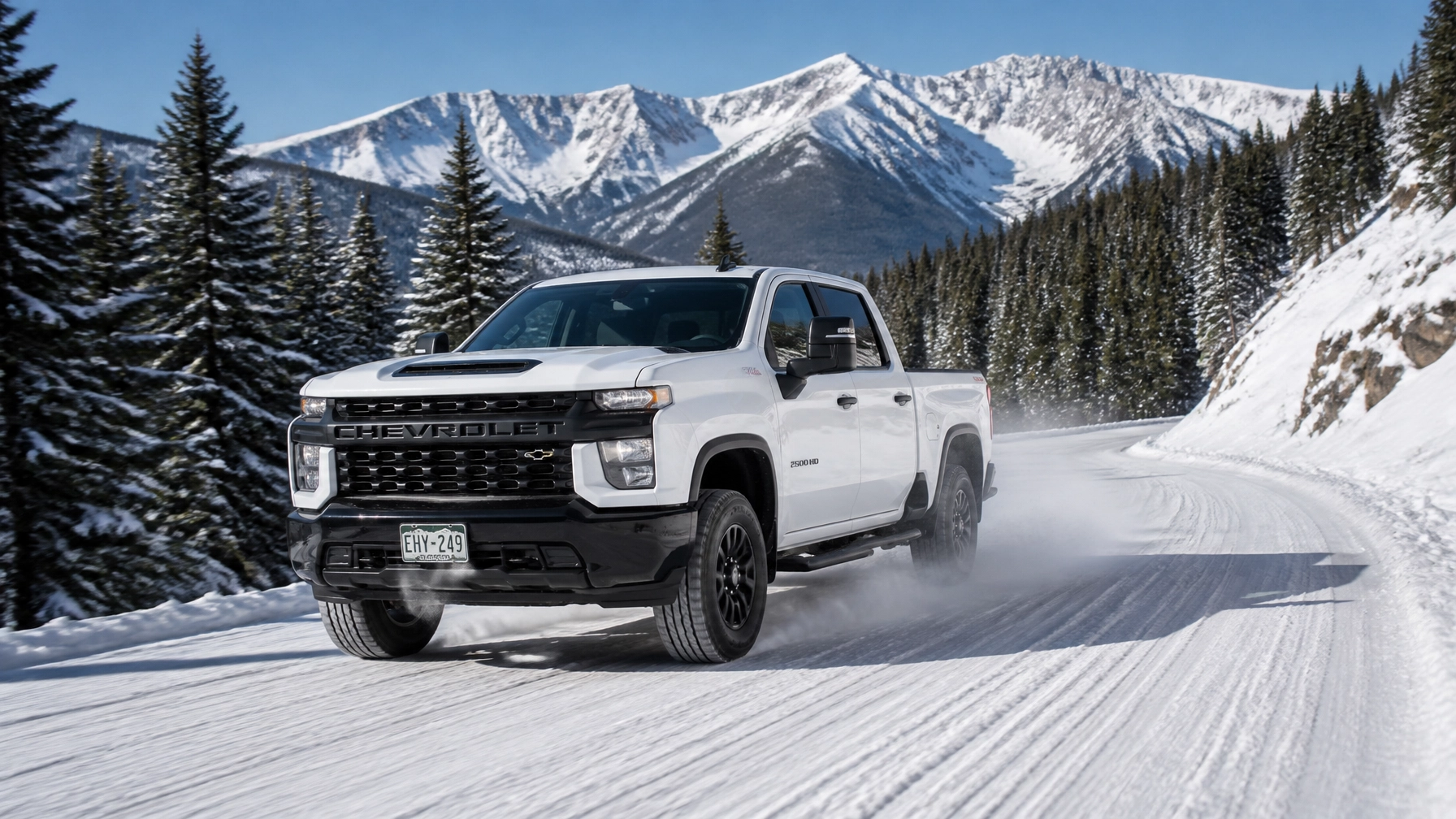 White Chevrolet Silverado 2500HD navigating snowy mountain roads near Colorado Springs CO