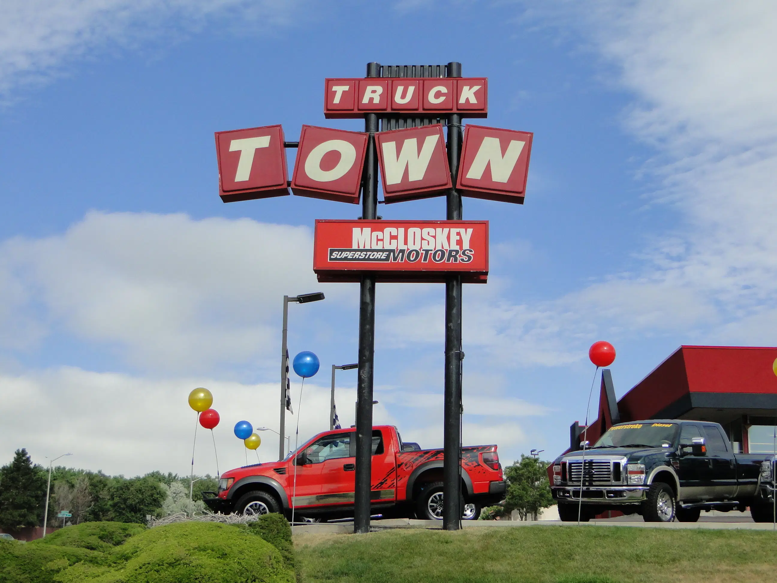 Large selection of pre-owned cars and SUVs on the McCloskey Motors lot with mountain views