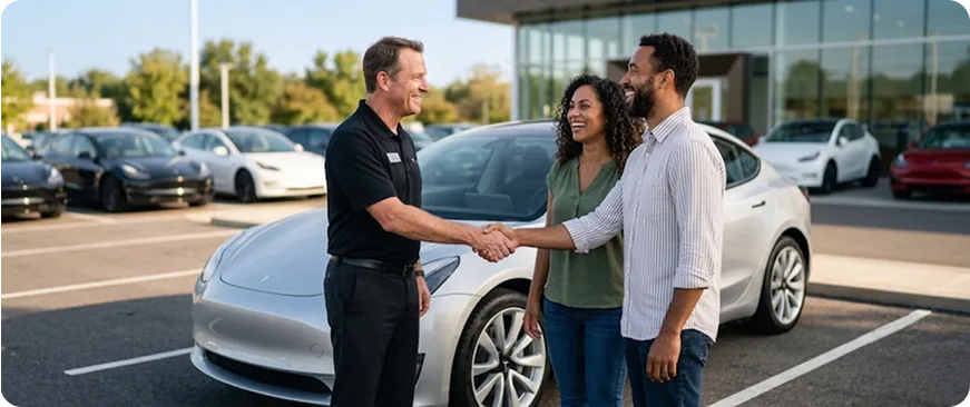 Salesperson shaking hands with a happy customer beside a vehicle at the dealership