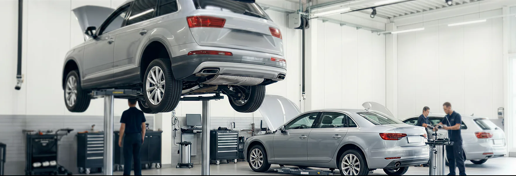 European SUV and sedan being serviced on lifts inside the Merit Auto Group service center
