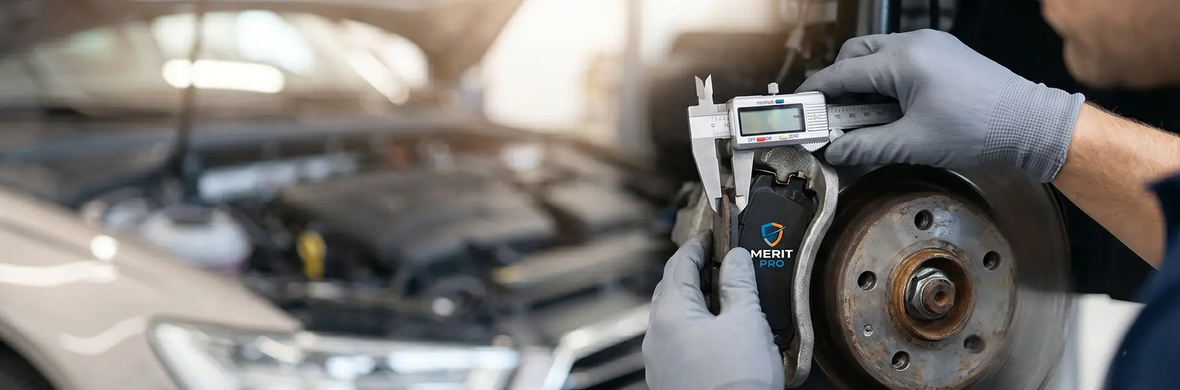 Technician measuring a worn brake pad and rotor with a caliper gauge during a brake inspection