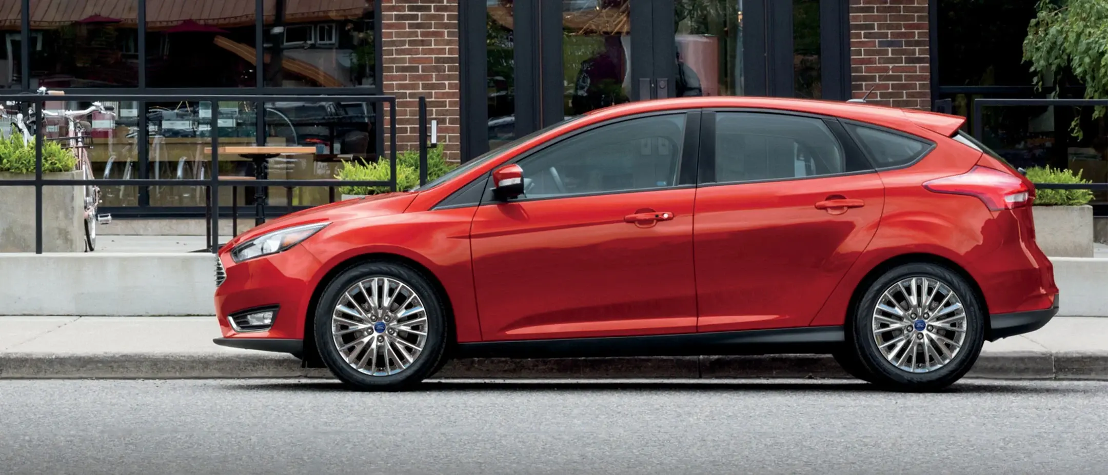 Red Ford Focus hatchback parked curbside by a cafe