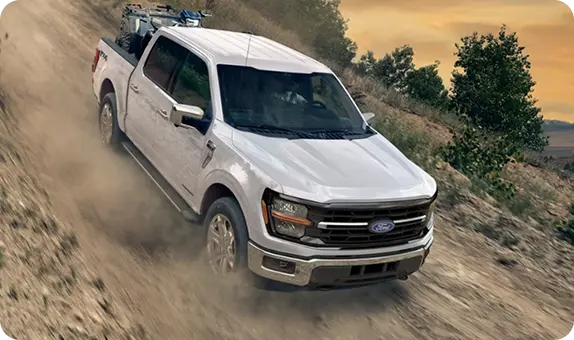 White Ford F-150 climbing a dirt trail, powered by its strong gas engine lineup