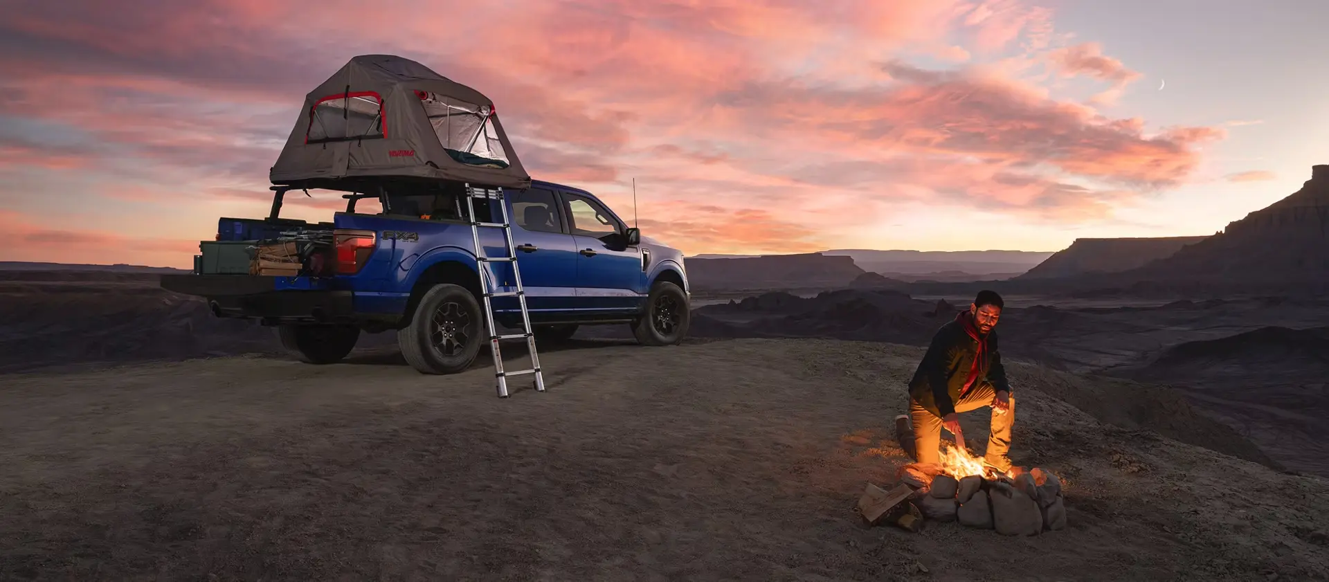 Blue Ford F-150 at a desert campsite with a rooftop tent at sunset