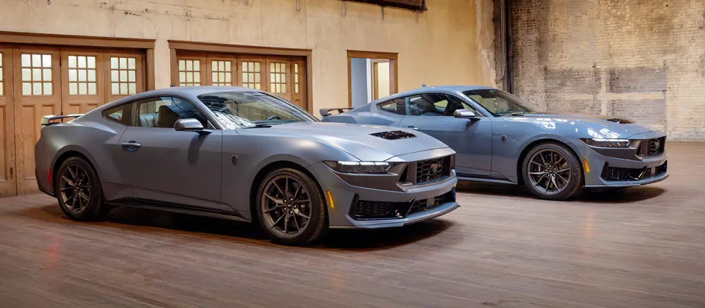 Two Ford Mustang Dark Horse coupes parked indoors, front three-quarter view