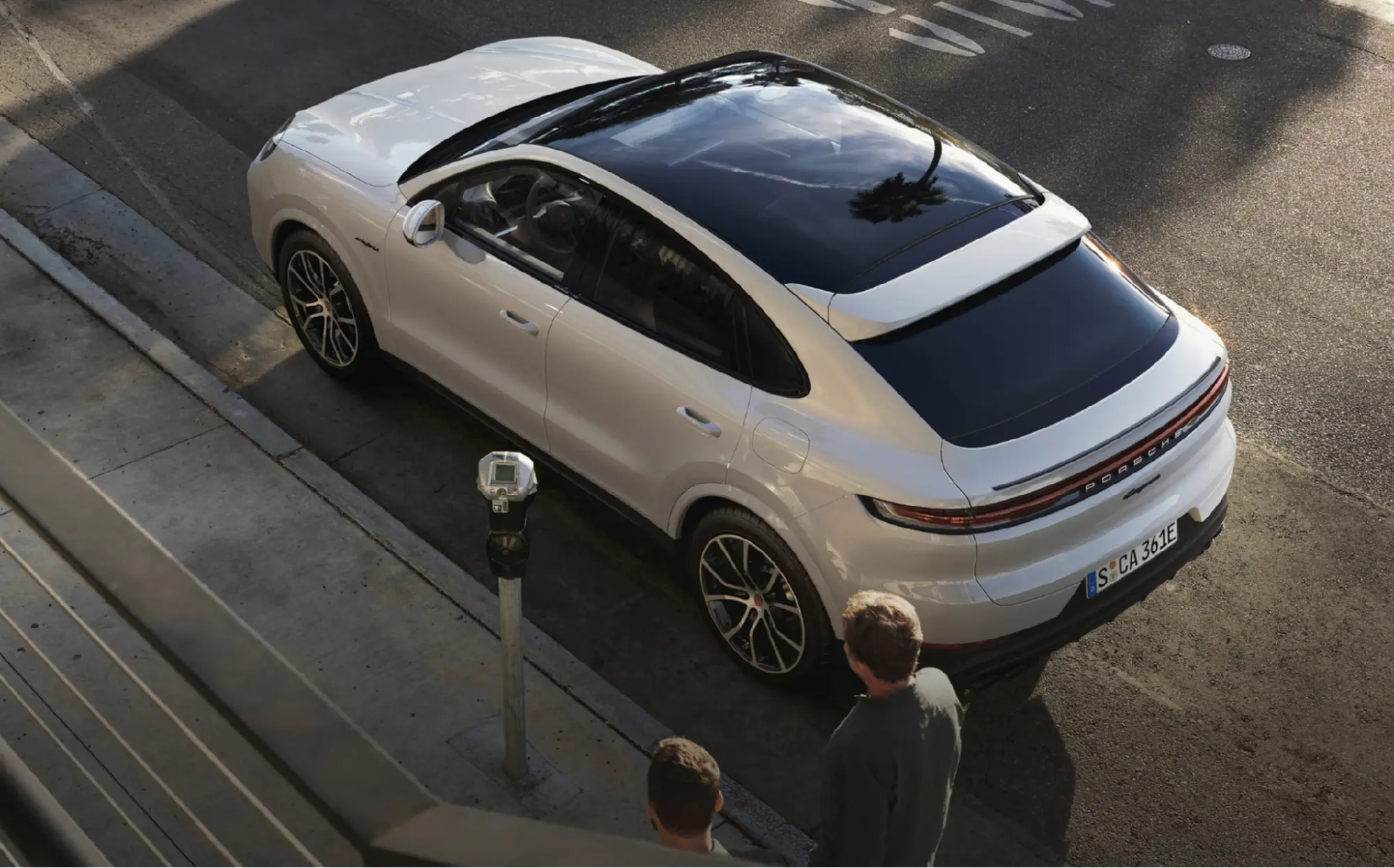 Overhead view of a white Porsche Cayenne Coupe parked curbside next to a parking meter
