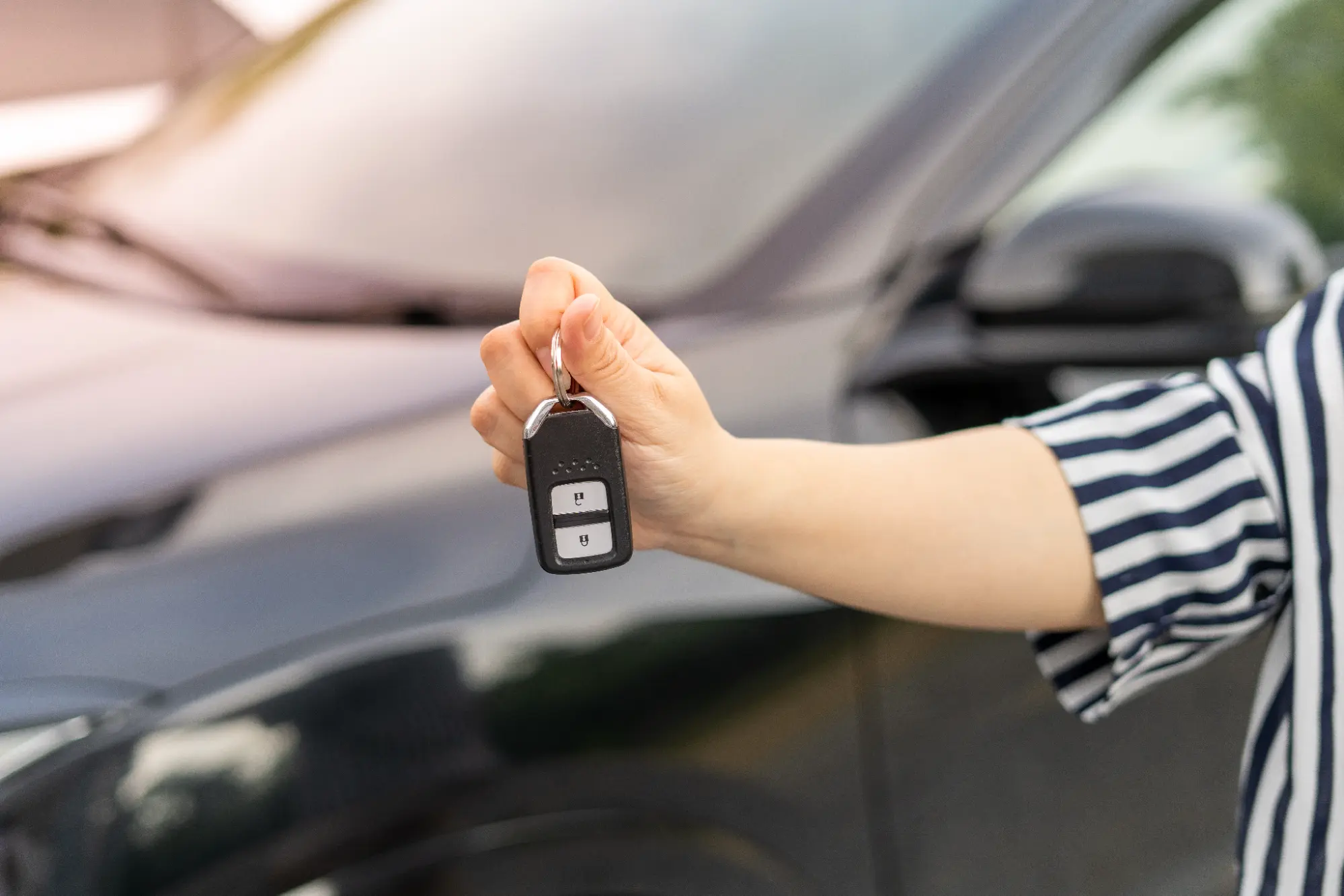 A person holding up a car key fob