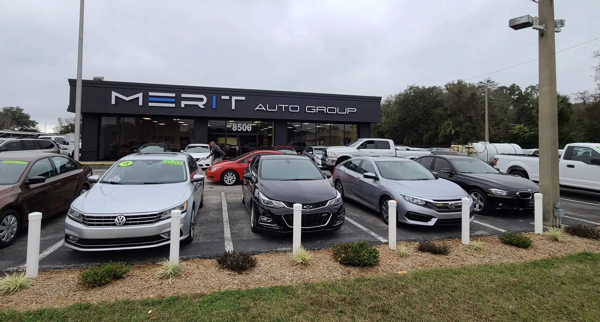 Merit Auto Group dealership storefront in Jacksonville, FL, with a lineup of pre-owned cars parked out front