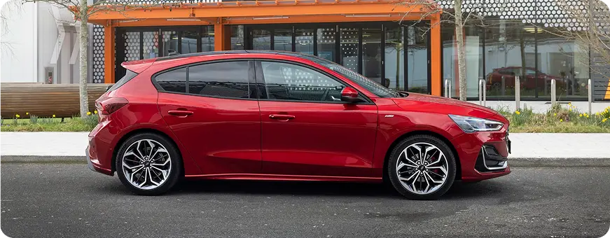Red Ford Focus hatchback parked, side profile
