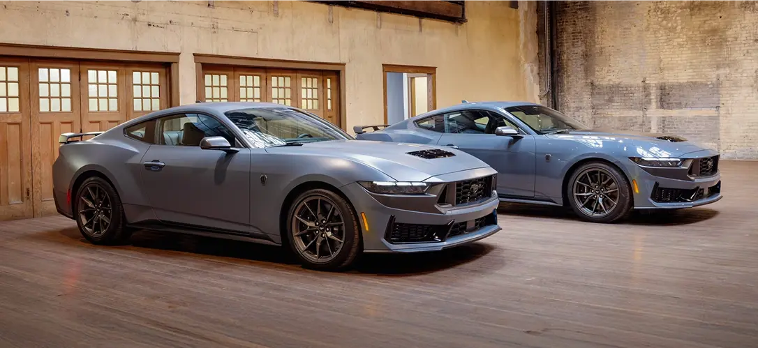 Two Ford Mustang Dark Horse coupes parked indoors, front view