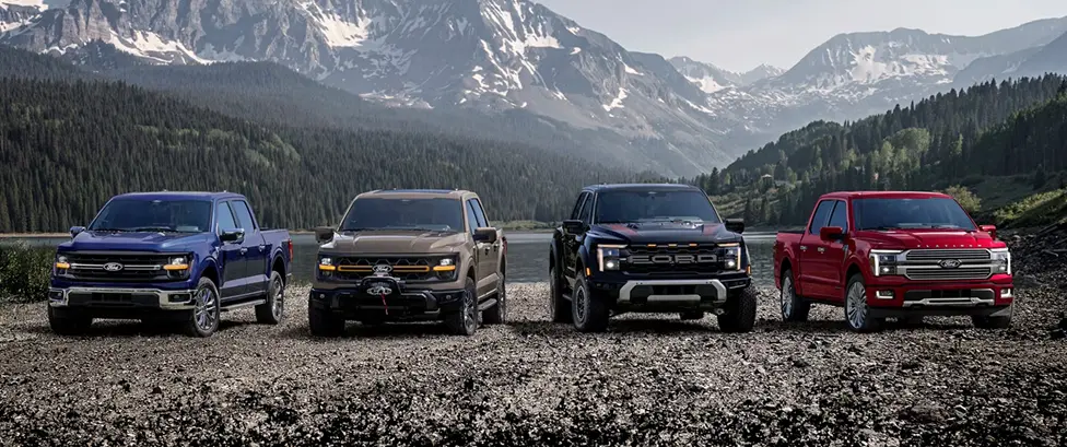 Lineup of Ford F-150 trucks parked by a mountain lake