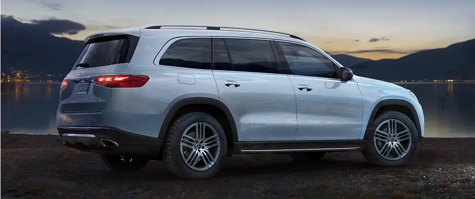 Silver Mercedes-Benz GLS parked beside a waterfront at dusk