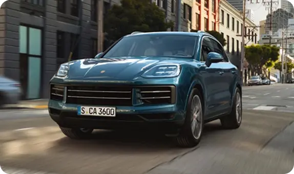 Teal Porsche Cayenne in motion on a city street