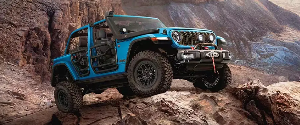 Blue Jeep Wrangler climbing over rocky off-road terrain