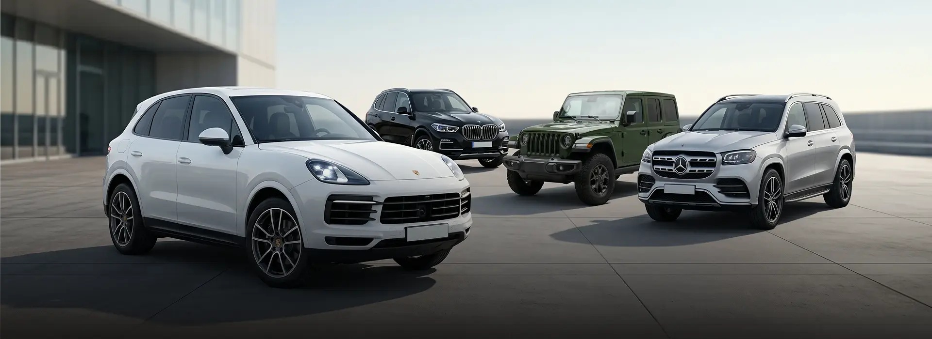 A white Porsche Cayenne, dark BMW X5, green Jeep Wrangler and silver Mercedes-Benz GLS lined up at the Merit Auto Group dealership