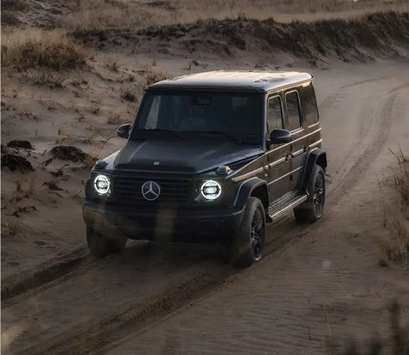 Dark Mercedes-Benz G-Class driving on a dirt road