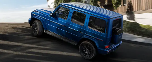 Blue Mercedes-Benz G-Class side profile on a road
