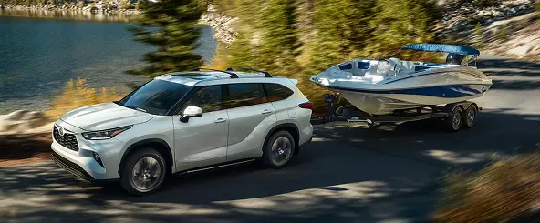 White Toyota Highlander towing a boat on a trailer