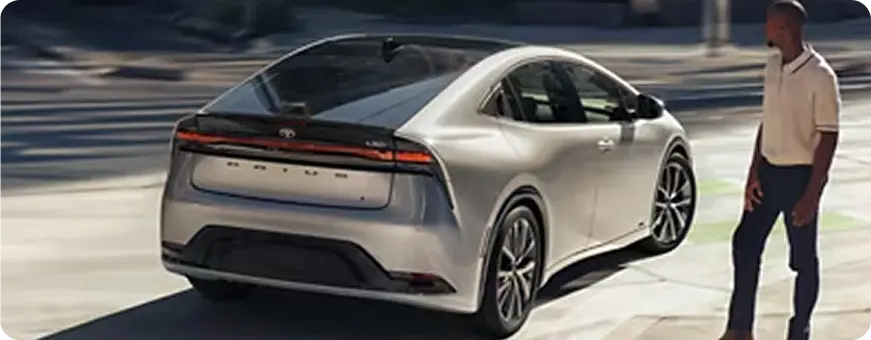 Silver Toyota Prius Prime, rear three-quarter view with a person walking nearby