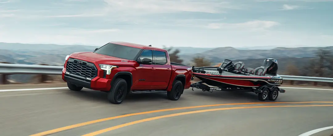 Red Toyota Tundra towing a bass boat on a mountain highway