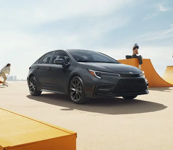 Gray Toyota Corolla parked by a skate ramp, front three-quarter view