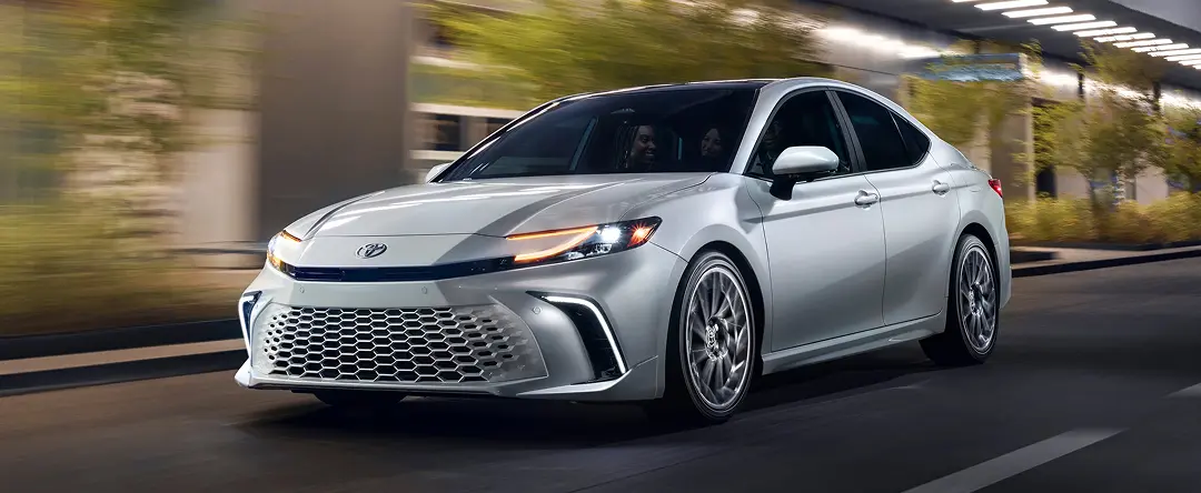 Silver Toyota Camry driving on a city street, front three-quarter view