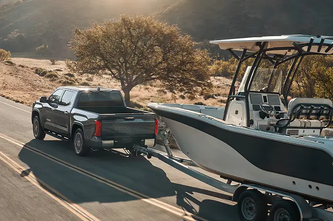 Black Toyota Tundra towing a center-console boat on a country road