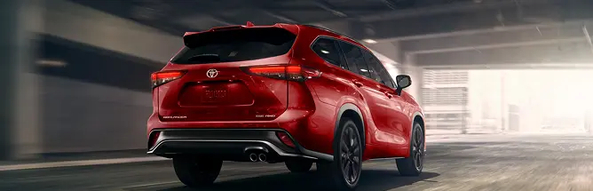Red Toyota Highlander driving, rear three-quarter view