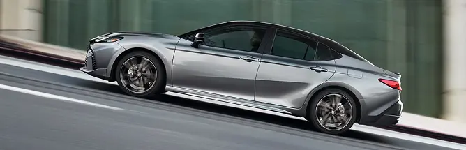 Silver Toyota Camry driving, rear three-quarter view