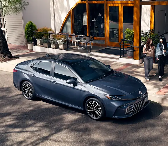 Blue-gray Toyota Camry parked outside a restaurant, front three-quarter view