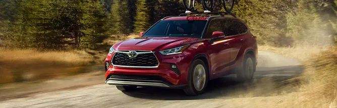 Red Toyota Highlander driving on a dirt trail, front three-quarter view
