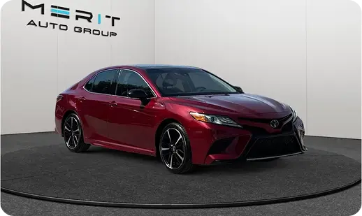 Red Toyota Camry sedan on a studio turntable, front three-quarter view
