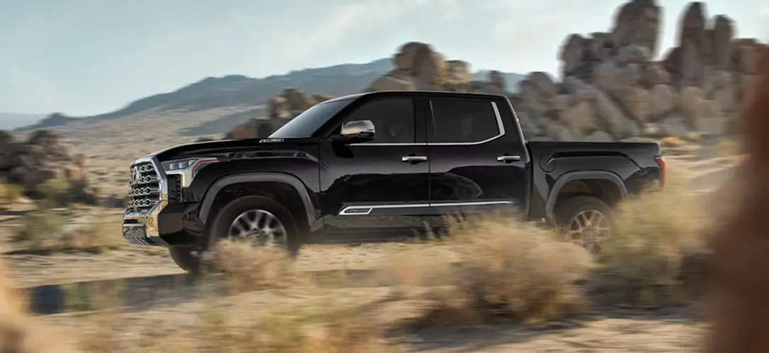 Black Toyota Tundra i-FORCE MAX driving through the desert, front three-quarter view