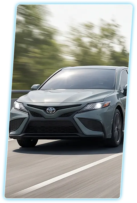 Gray Toyota Camry front view against a city skyline
