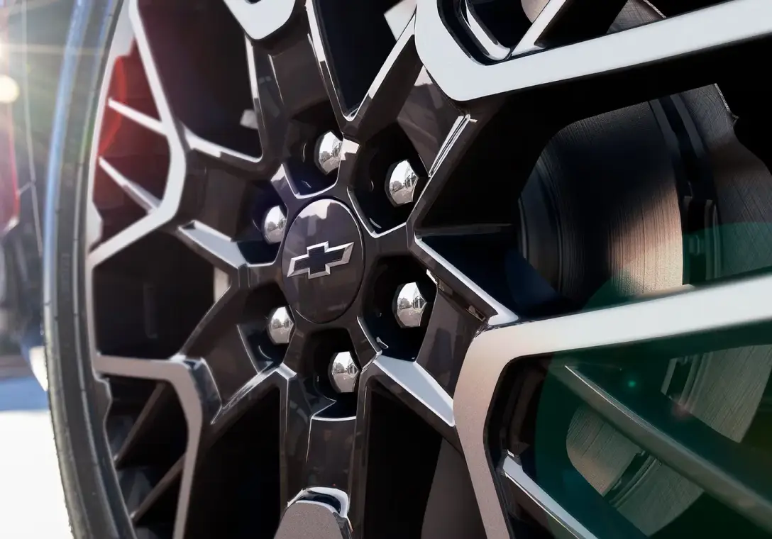 Close-up of a black Chevrolet alloy wheel with chrome lug nuts and a Chevy bowtie center cap