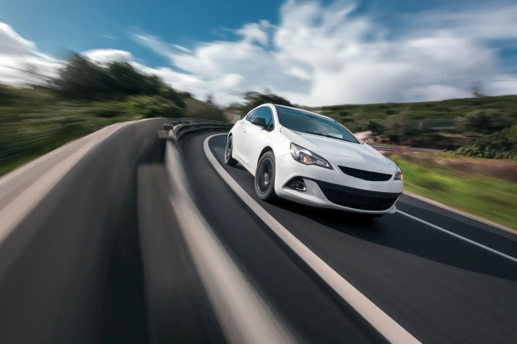 White vehicle driving on scenic road demonstrating performance and efficiency comparison