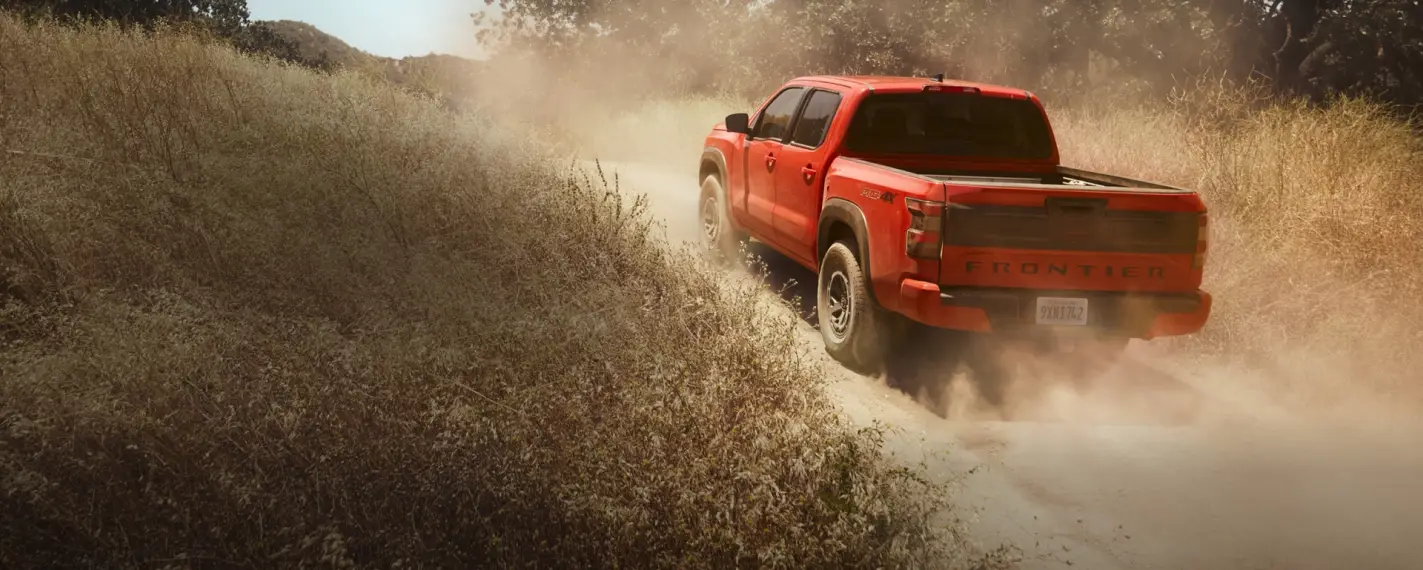 2025 Red Nissan Frontier out on a dirt road