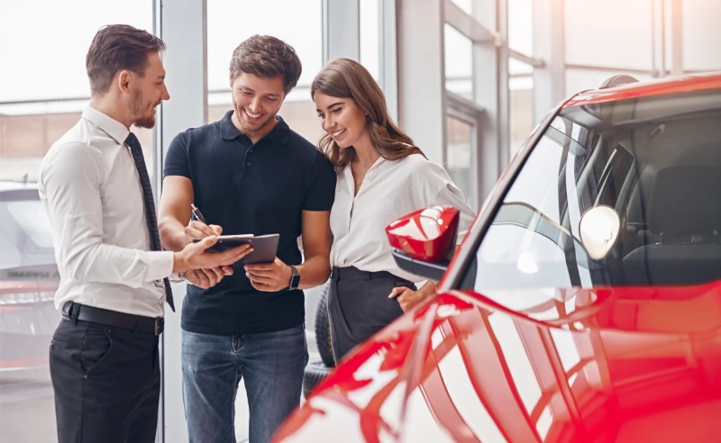 man and woman at a car dealership discussing car financing