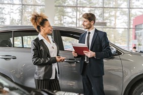 man and woman at a car dealership discussing car financing