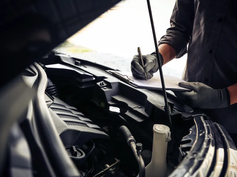 Tech performing safety inspection in engine bay of a vehicle