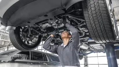 A technician working underneath a vehicle on a vehicle lift rack.