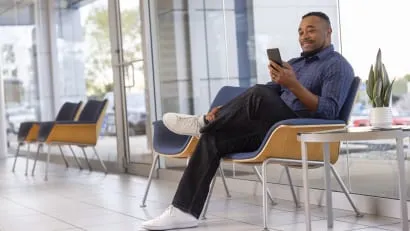 A customer happily waits in the Brown Daub Chevrolet service waiting room with free Wi-Fi.